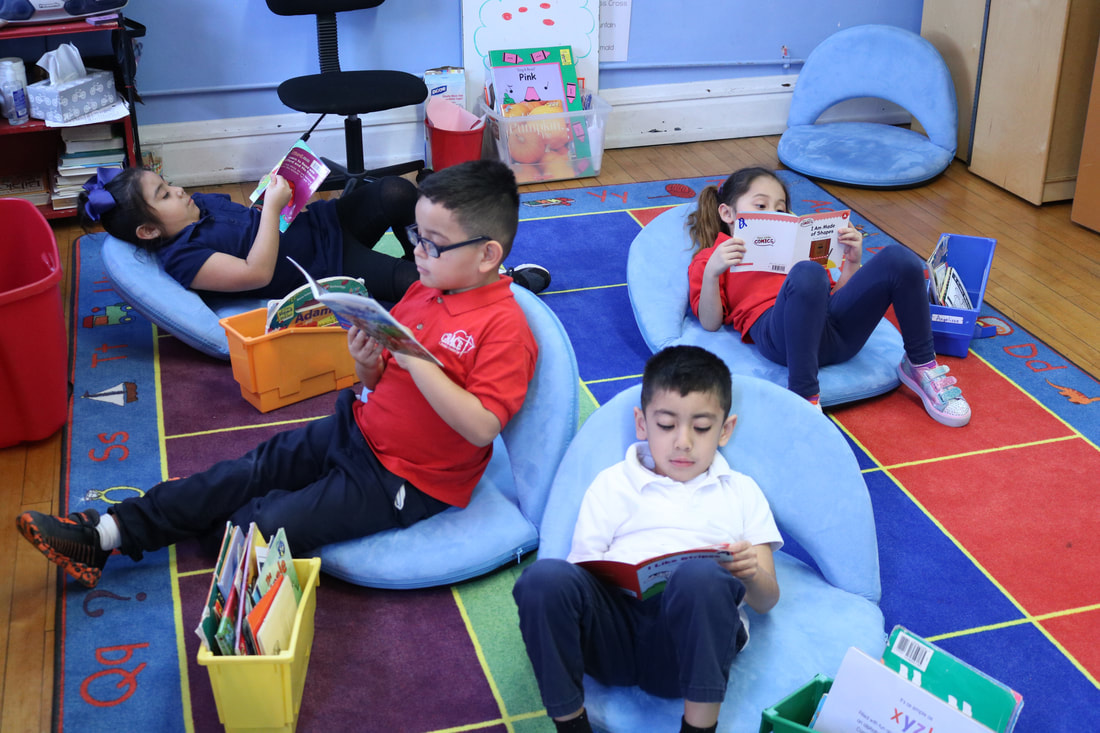Two male and two female students sit on bean bag chairs reading books.